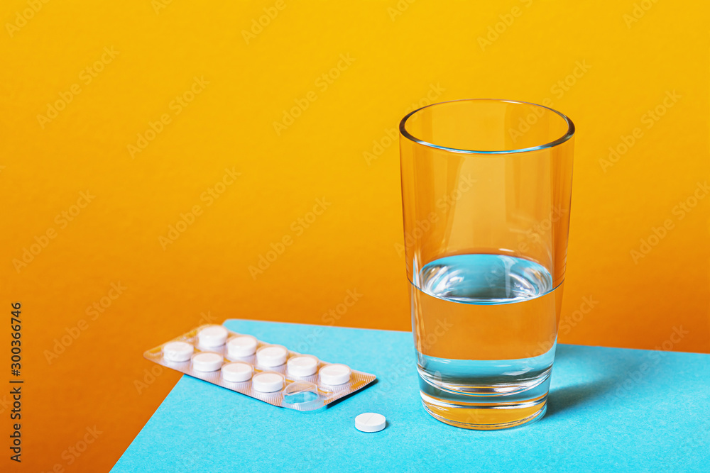 Aspirin pills and a glass of water on the table. Treatment of cold Aspirin pills and a glass of water on the table. Treatment of cold