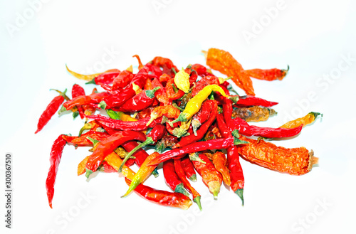 dried hot chili peppers, yellow and green pods on a light background