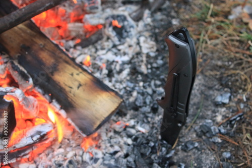 Burning bonfire and red flame, a knife stuck into the ground nearby