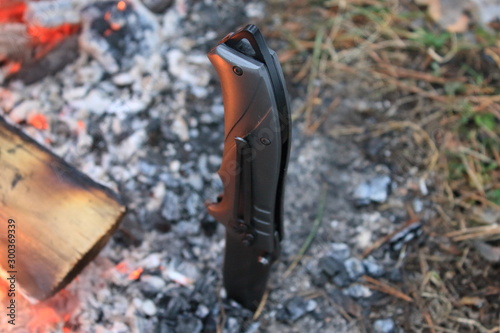 Burning bonfire and red flame, a knife stuck into the ground nearby