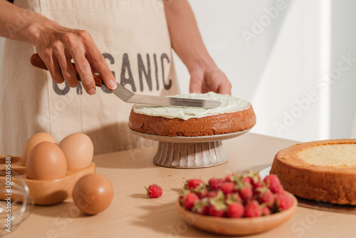 Fotografia, Obraz Spreading cream on sponge cake. Making red velvet process