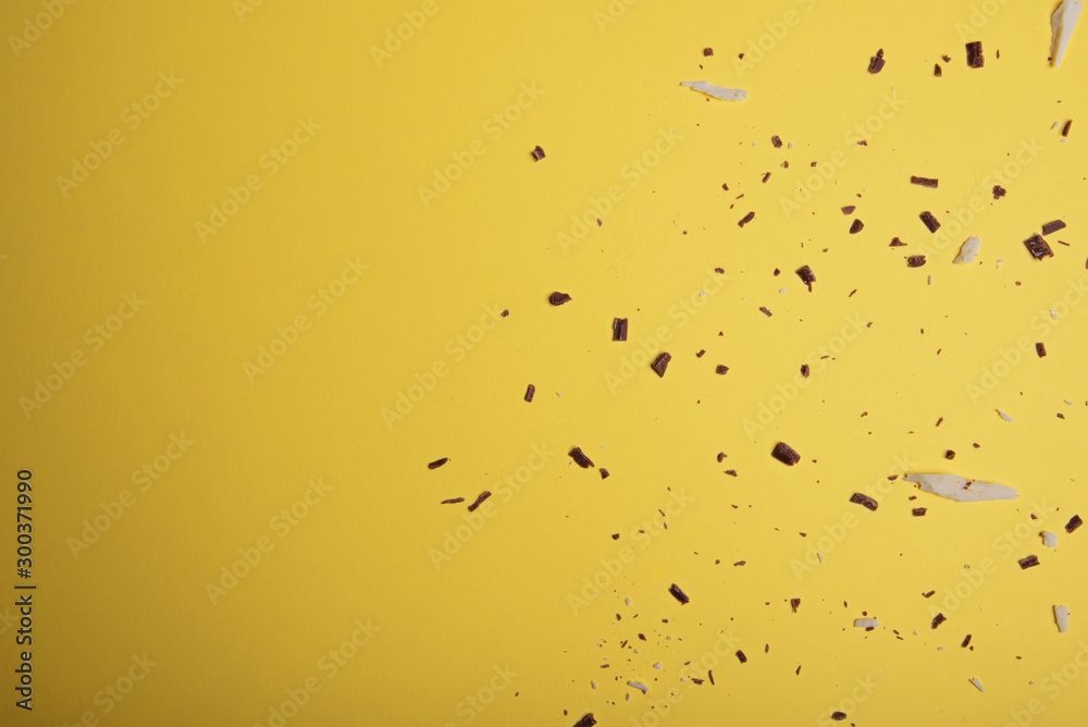 White and dark chocolate pieces and chipson on a bright yellow background. View from above. Flat lay. White and dark chocolate pieces and chipson on a bright yellow background. View from above. Flat lay.