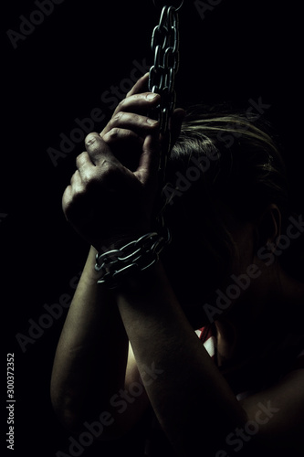 White women's hand are on the floor chained metal chains close-up on a black background, toned to a retro film