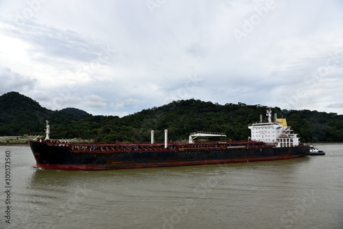 Bulk carrier ship transiting through the Panama Canal on a cloudy day. 