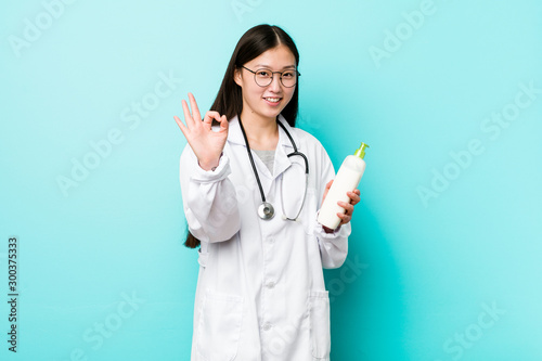 Young asian dermatologist girl cheerful and confident showing ok gesture.