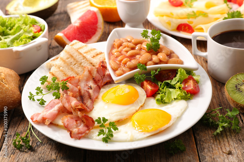 english full breakfast with fried egg, bacon,cheese, toast, coffee and fruits