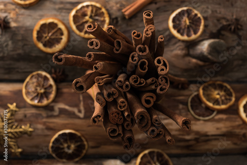 top view of dried citrus slices with cinnamon sticks and decorative snowflakes on wooden background