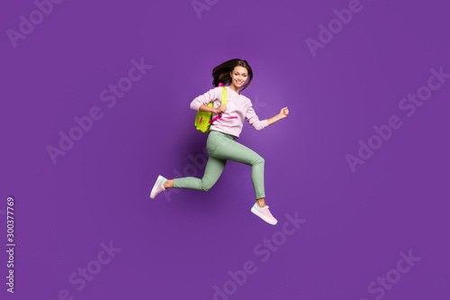 Full length body size profile side view of nice attractive slim fit slender thin cheerful girl jumping running highschool isolated on bright vivid shine vibrant purple violet lilac color background