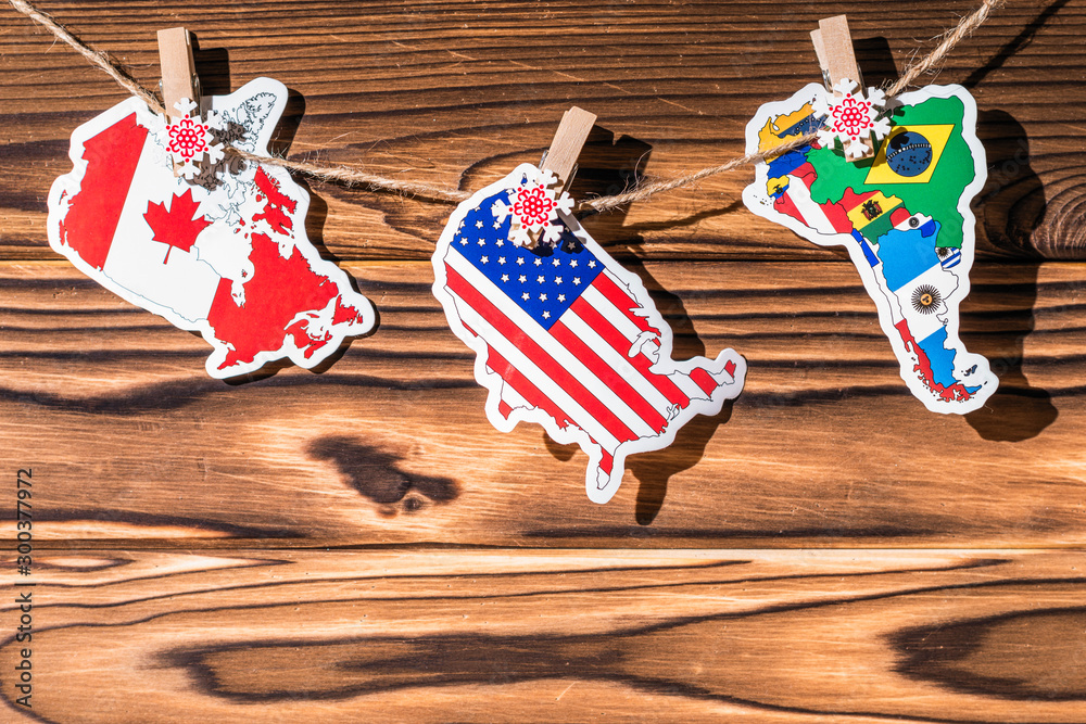 Obraz premium Map (flag) of North, South America, Canada hanging on a rope on wooden clothespins. Rustic Christmas decoration. Wooden boards background. USA. Concept