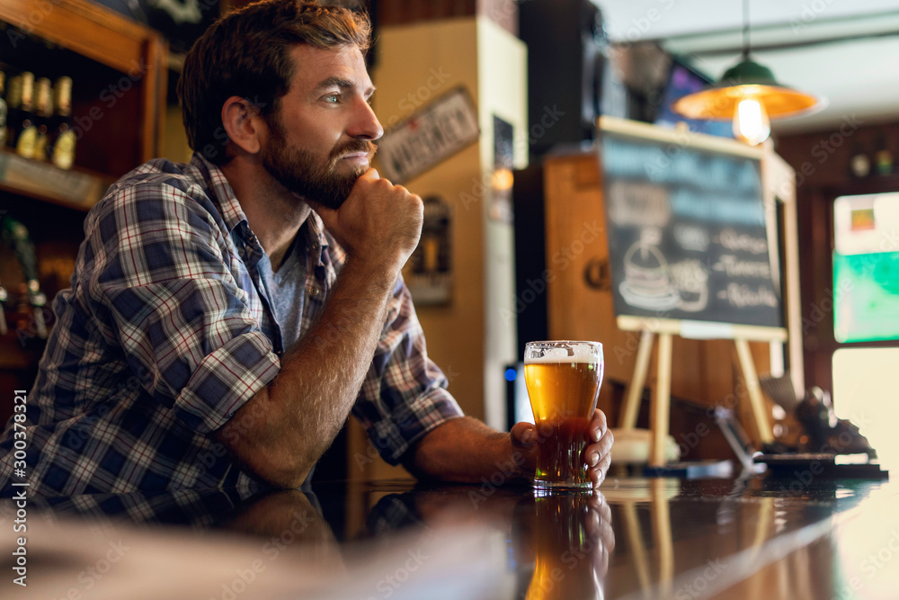 Thoughtful man holding beer glass while sitting in the beer bar Thoughtful man holding beer glass while sitting in the beer bar