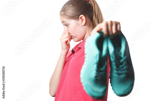 girl holds stinky sneakers and closes her hand with her nose