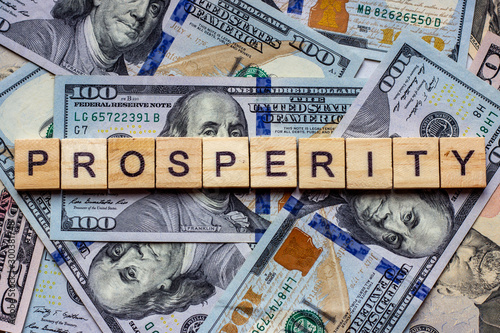 The word prosperity on dollar usa background. Welfare, sufficiency and wealth concept photo
