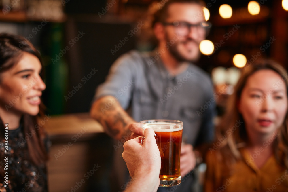 Friends standing in bar and toasting with beer.