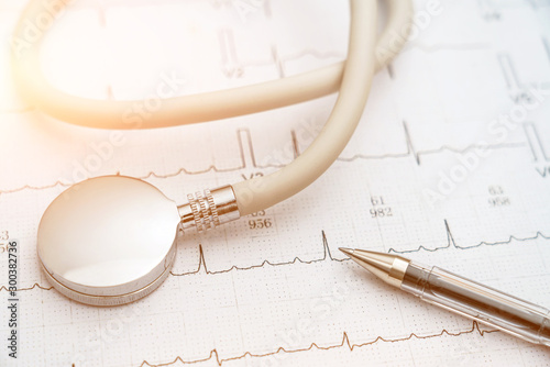 Stethoscope and a pen in the background of electrocardiographic drawing photo