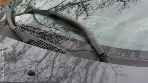 Water or cleaner spraying from windshield washer nozzle to glass, with wipers moving