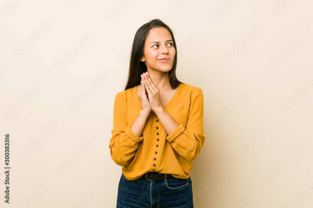 Young hispanic woman against a beige background making up plan in mind, setting up an idea. Young hispanic woman against a beige background making up plan in mind, setting up an idea.