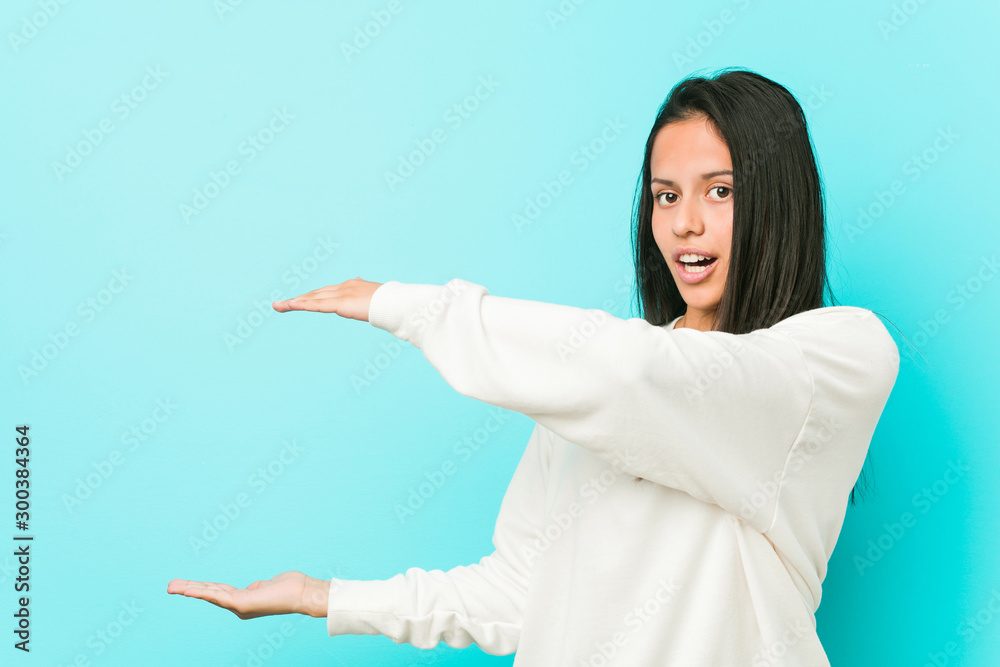 Young pretty hispanic woman shocked and amazed holding a copy space between hands. Young pretty hispanic woman shocked and amazed holding a copy space between hands.