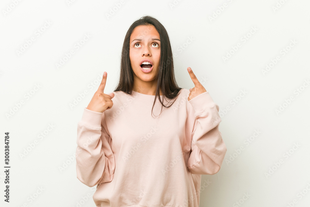 Young cute hispanic teenager woman pointing upside with opened mouth. Young cute hispanic teenager woman pointing upside with opened mouth.