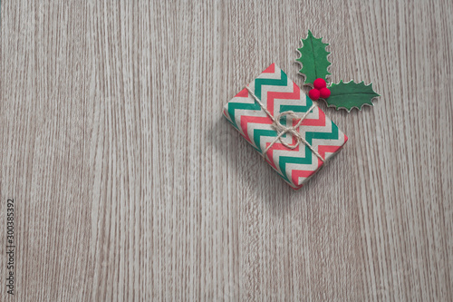 Christmas composition A red and green gift next to the mistletoe on a wooden background