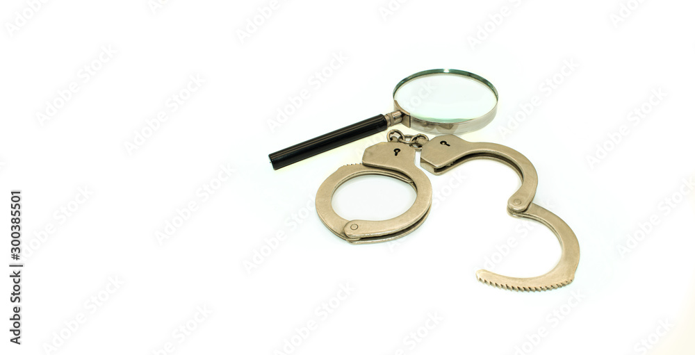 Magnifier and handcuffs on a white background Magnifier and handcuffs on a white background