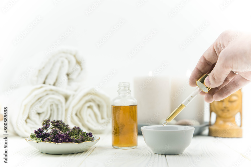 Spa treatment bottle of natural organic oil essence serum collagen. Towel, aromatic candles, flowers, massage brush and Buddha on white background. Copy space for text. Beautiful woman hands. Oil drop Spa treatment bottle of natural organic oil essence serum collagen. Towel, aromatic candles, flowers, massage brush and Buddha on white background. Copy space for text. Beautiful woman hands. Oil drop