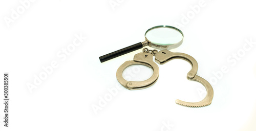 Magnifier and handcuffs on a white background