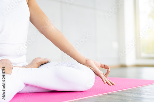 Woman doing yoga exercise in the indoor gym close up with copy space background. Concept of good health and wellness.