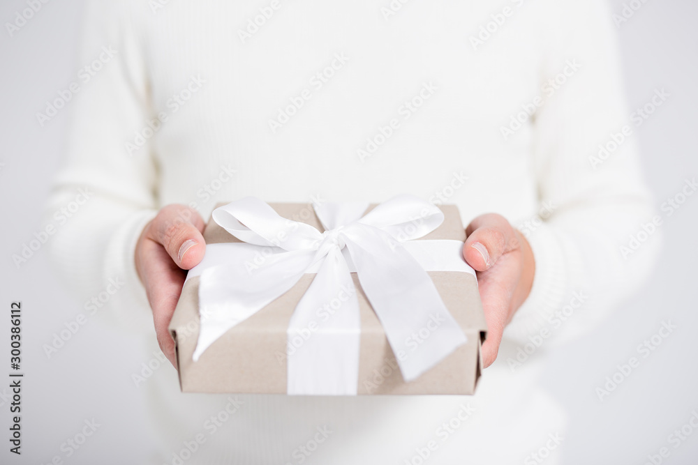 Christmas or Valentine's day concept - gift box in male hands over gray Christmas or Valentine's day concept - gift box in male hands over gray