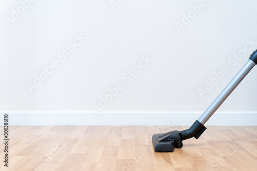 Modern vacuum head on wooden floor with copy space, housekeeper cleaning a room by using vacuum.
