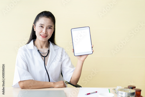 Asian woman doctor showing an empty white screen tablet, concept of maketing and commucication in medical service and hospital. photo