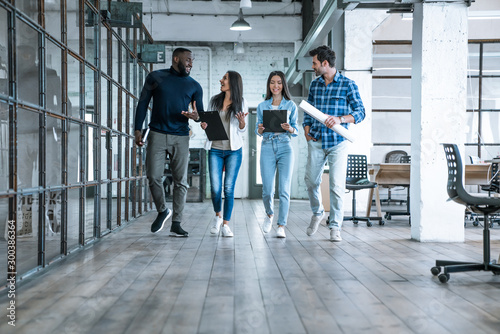 On the way to business meeting. Full length of young modern people in smart casual wear having a discussion while walking through the office