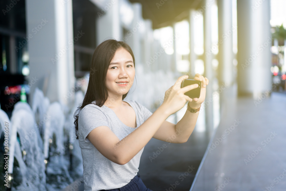 Beautiful Asian woman using a smartphone for photography at the front of the airport.