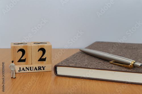 January  22, a calendar photo from the wood The table top consists of a book and pen that is ready to use. White background
