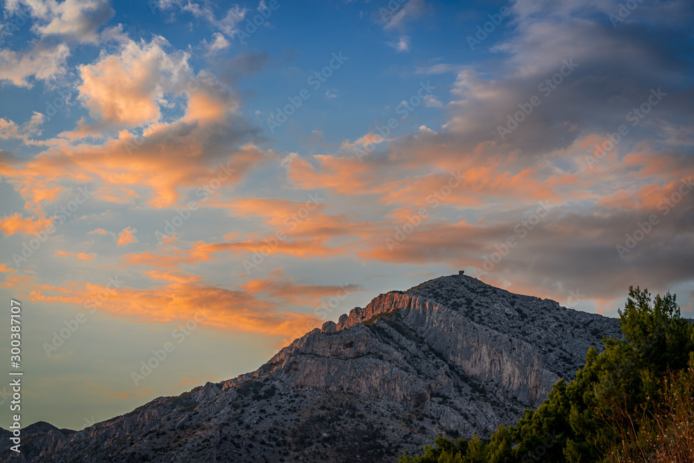 Beautiful sunset over Adriatic sea and mountains with orange clouds and blue sky in Dalmatia, Croatia