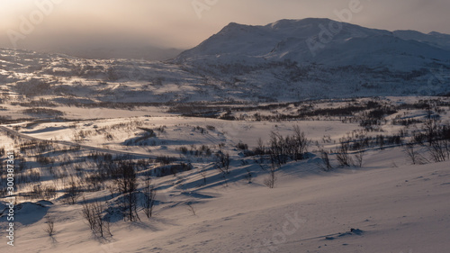 Morning in the winter mountains in northern Norway with a road passing through the snowy landscape