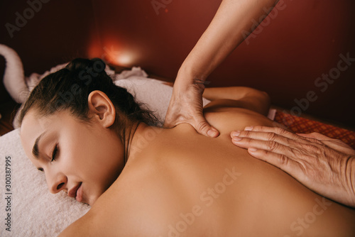 cropped view of masseur doing back massage to woman on massage mat