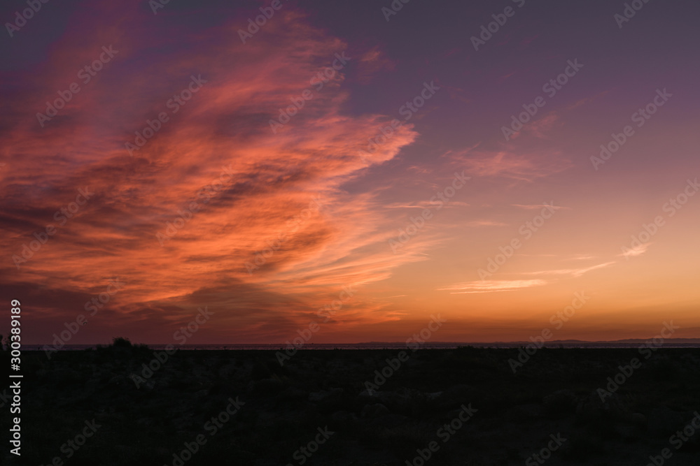 Magnifiques nuages de couleur orange et rose lors d'un coucher de soleil au dessus d'une plage