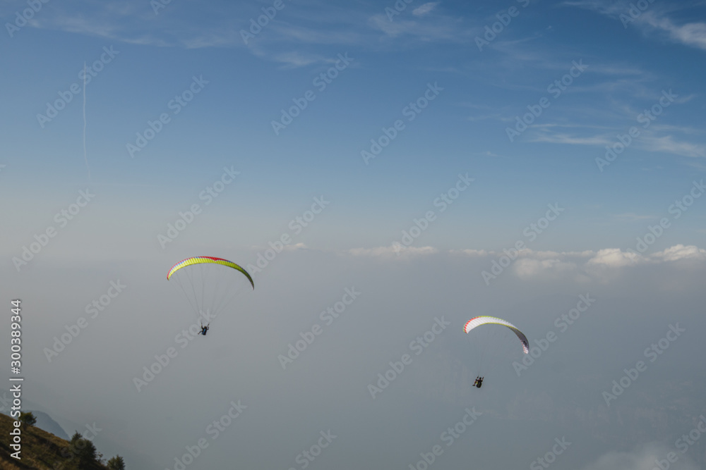 Paraglider flying over the Garda Lake,Panorama of the gorgeous Garda lake surrounded by mountains, Malcesine, Italy Paraglider flying over the Garda Lake,Panorama of the gorgeous Garda lake surrounded by mountains, Malcesine, Italy