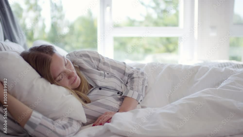 Tracking shot of peaceful woman wearing pajama sleeping in bed in morning Tracking shot of peaceful woman wearing pajama sleeping in bed in morning