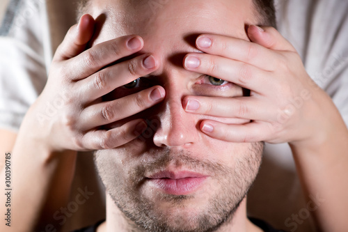 a man looks through the fingers of a woman  close up
