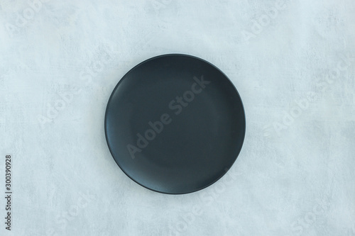 Empty black plate on dark stone background.