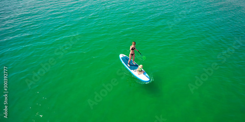 Little girl in a life vest sitting on the paddle board with mother © sarymsakov.com