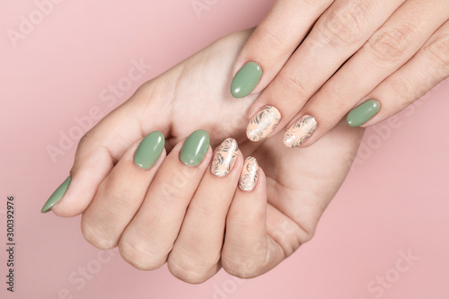 Closeup top view of beautiful hands of white woman isolated on pink pastel background. Fingernails with stylish trendy two colors faded manicure made with modern gel polish and silver stamping design. photo