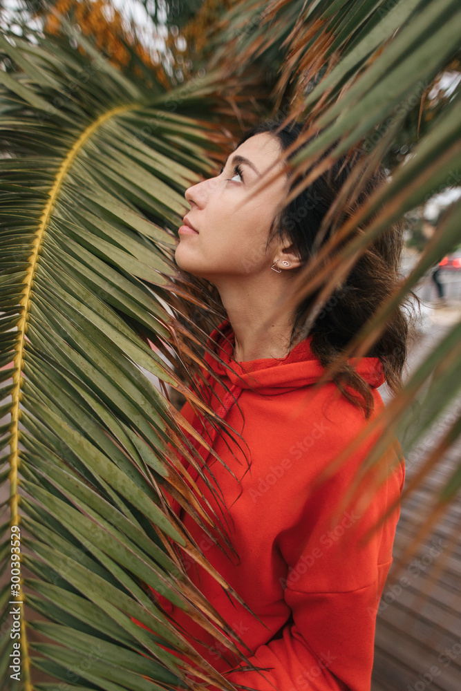 girl in a red sweater stands near a palm tree girl in a red sweater stands near a palm tree
