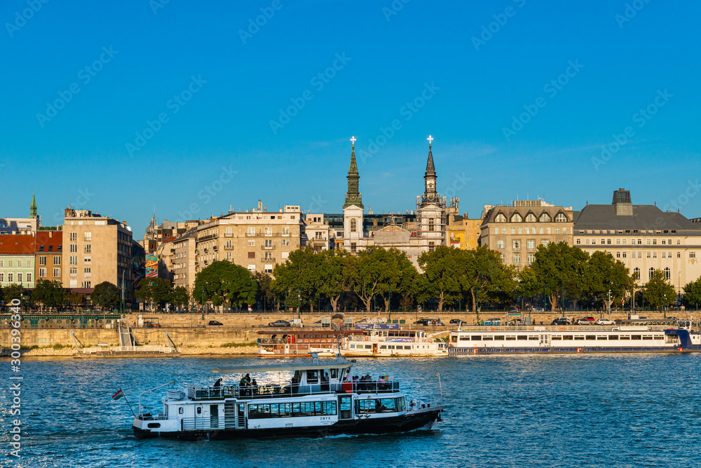 Budapest, Hungary - October 01, 2019: Cityscape of Budapest with Orthodox Cathedral of Our Lady with passenger boats on the Danube river, Budapest, Hungary.