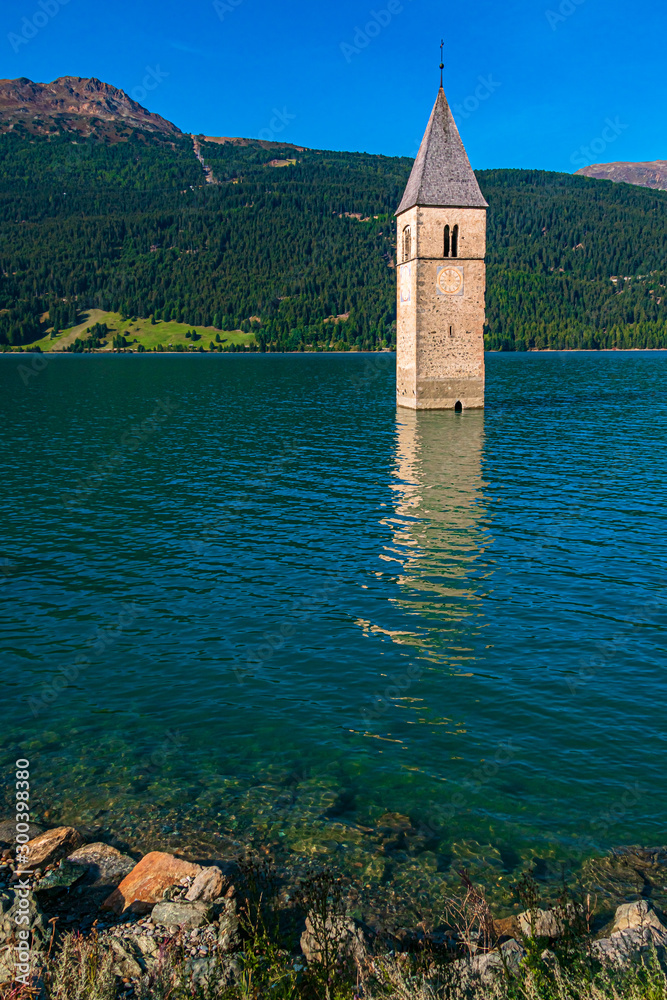 Beautiful alpine view of Lake Reschen with reflections and the famous submerged bell tower of Graun, Vinschgau, South Tyrol, Italy