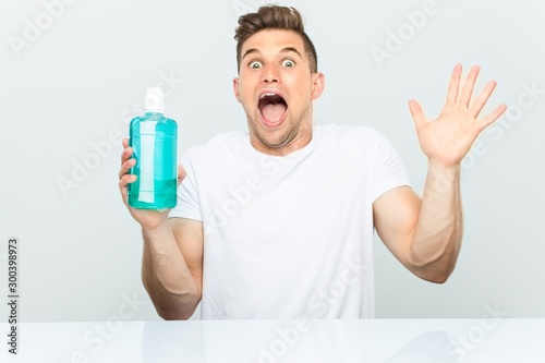 Young man holding a mouthwash celebrating a victory or success