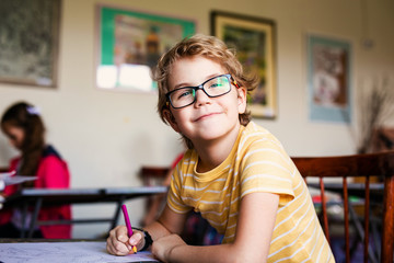 Blonde boy with glasses drawing. Group of elementary school pupils in classroom on art class. Russia, Krasnodar, May, 23, 2019