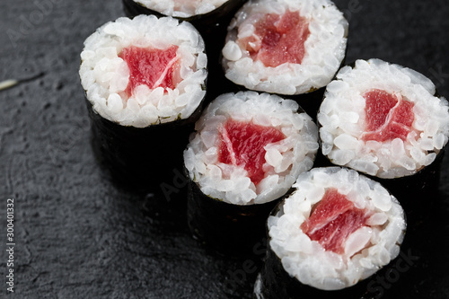 Obraz na płótnie Maki Sushi Rolls with tuna on black stone on dark background. Sushi menu. Japanese food. Closeup of delicious japanese food with sushi roll. Horizontal photo w salonie