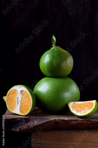 Green mandarins cut in halves and segments and whole sweetie on a wooden table